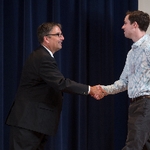 Doctor Smart shaking hands with an award recipient in a blue striped shirt